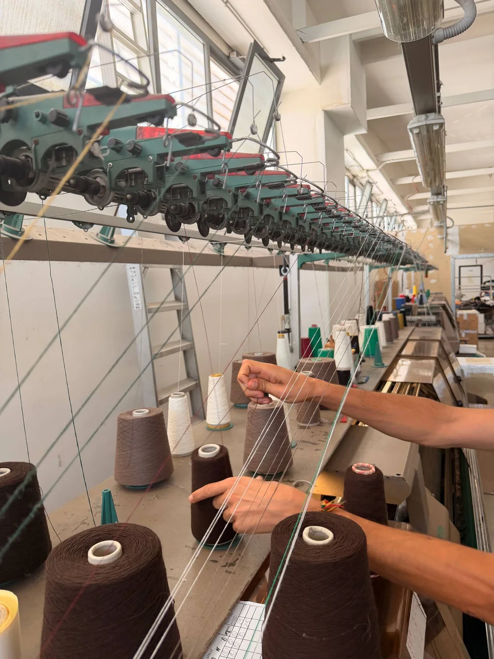 Hände fädeln Garn an der Strickmaschine ein